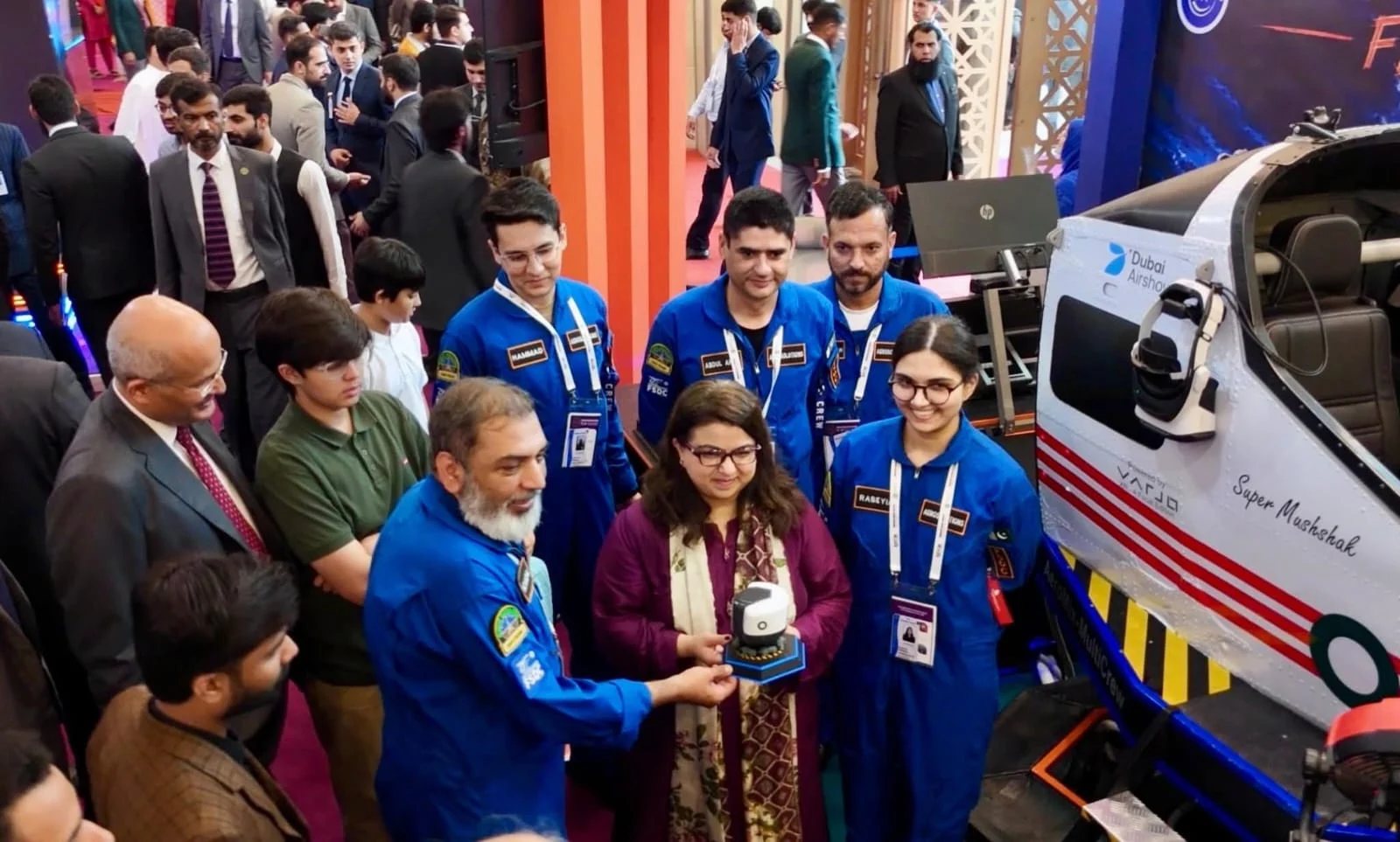 The Federal IT Minister receiving a memento from the FSDC Aerosolutions team beside the Super Mushshak simulator