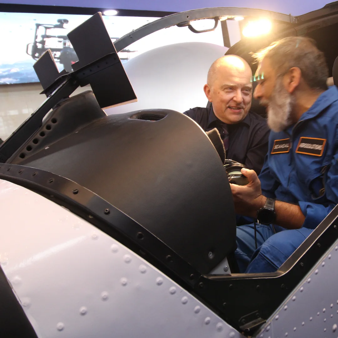An FSDC engineer briefing a visitor seated in the simulator cockpit